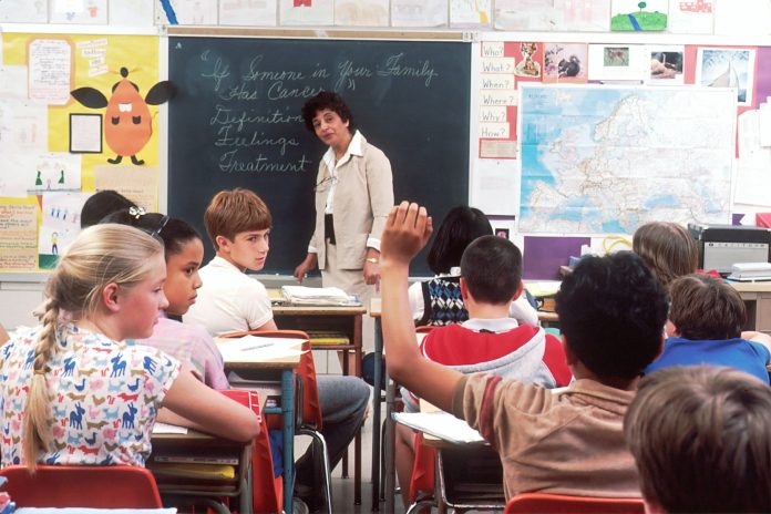 Anak-anak belajar bersama guru di ruang kelas sekolah